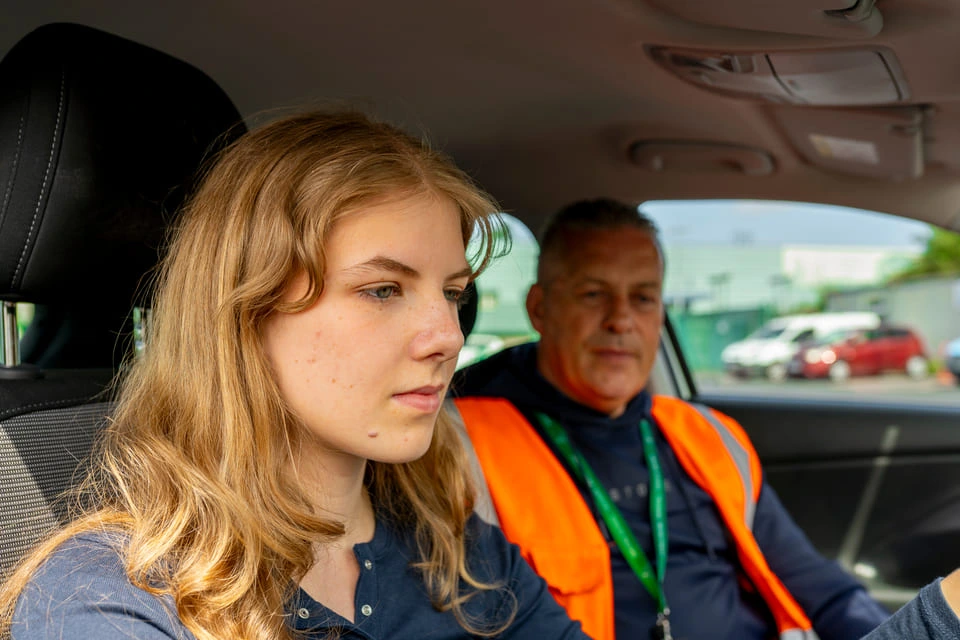 Inside_a_car,_a_woman_is_seated_next_to_a_driving_instructor_ISM_Driving_lessons