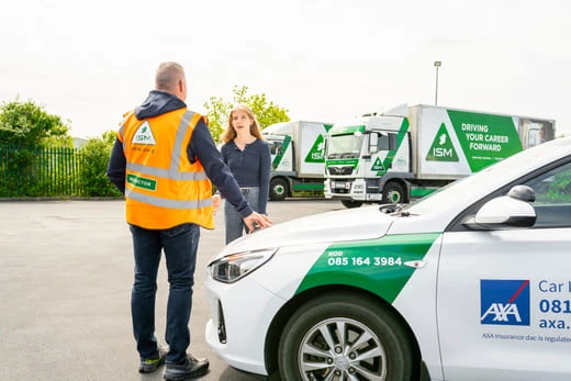 A_driving_instructor_and_young_woman_stand_beside_a_car_ISM_Driving_lessons