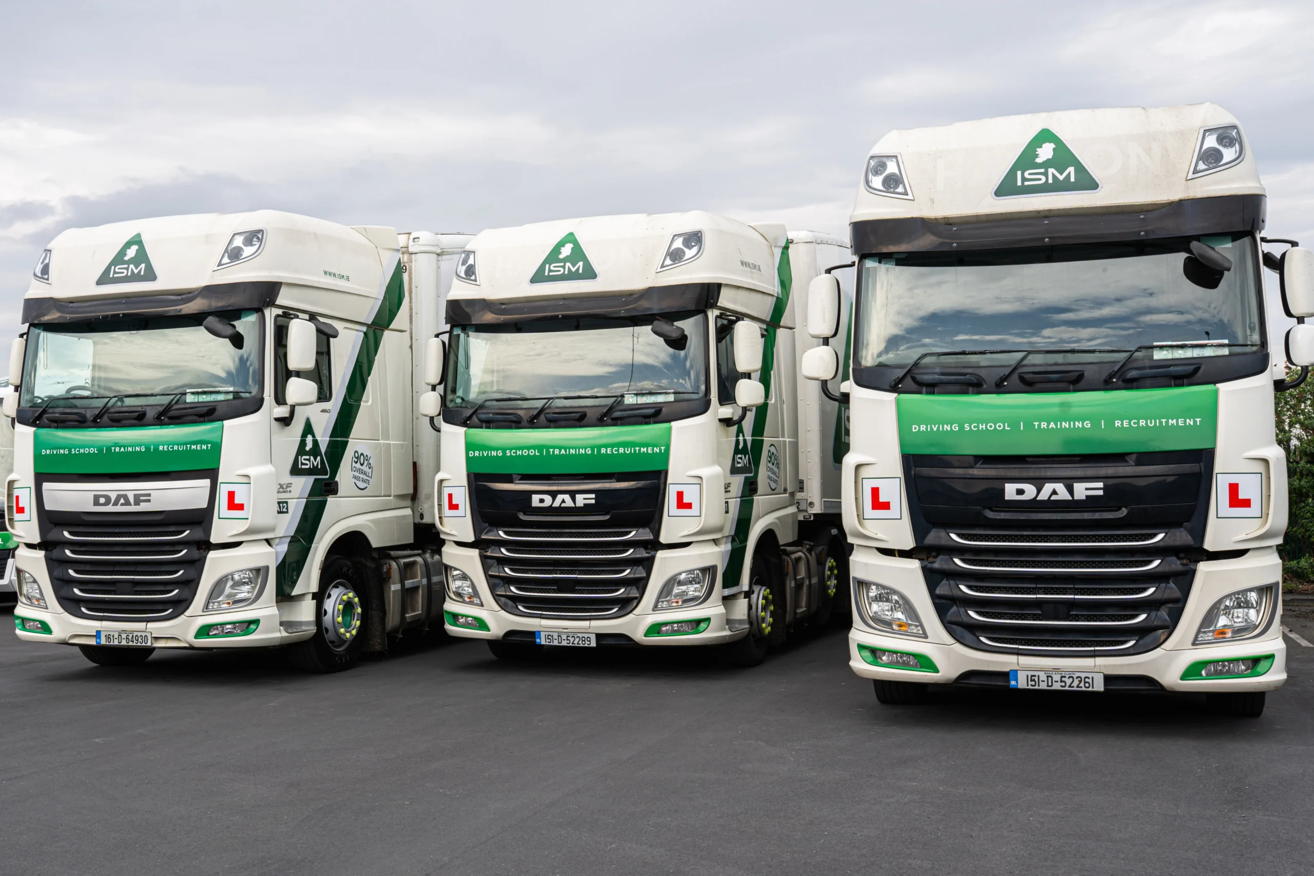 Three_green_and_white_trucks_parked_in_a_row_on_a_paved_surface _ISM Training_and_Recruitment