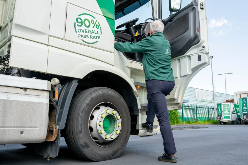 A_man_in_a_green_shirt_stands_alongside_a_truck_ISM_Driving_Lessons