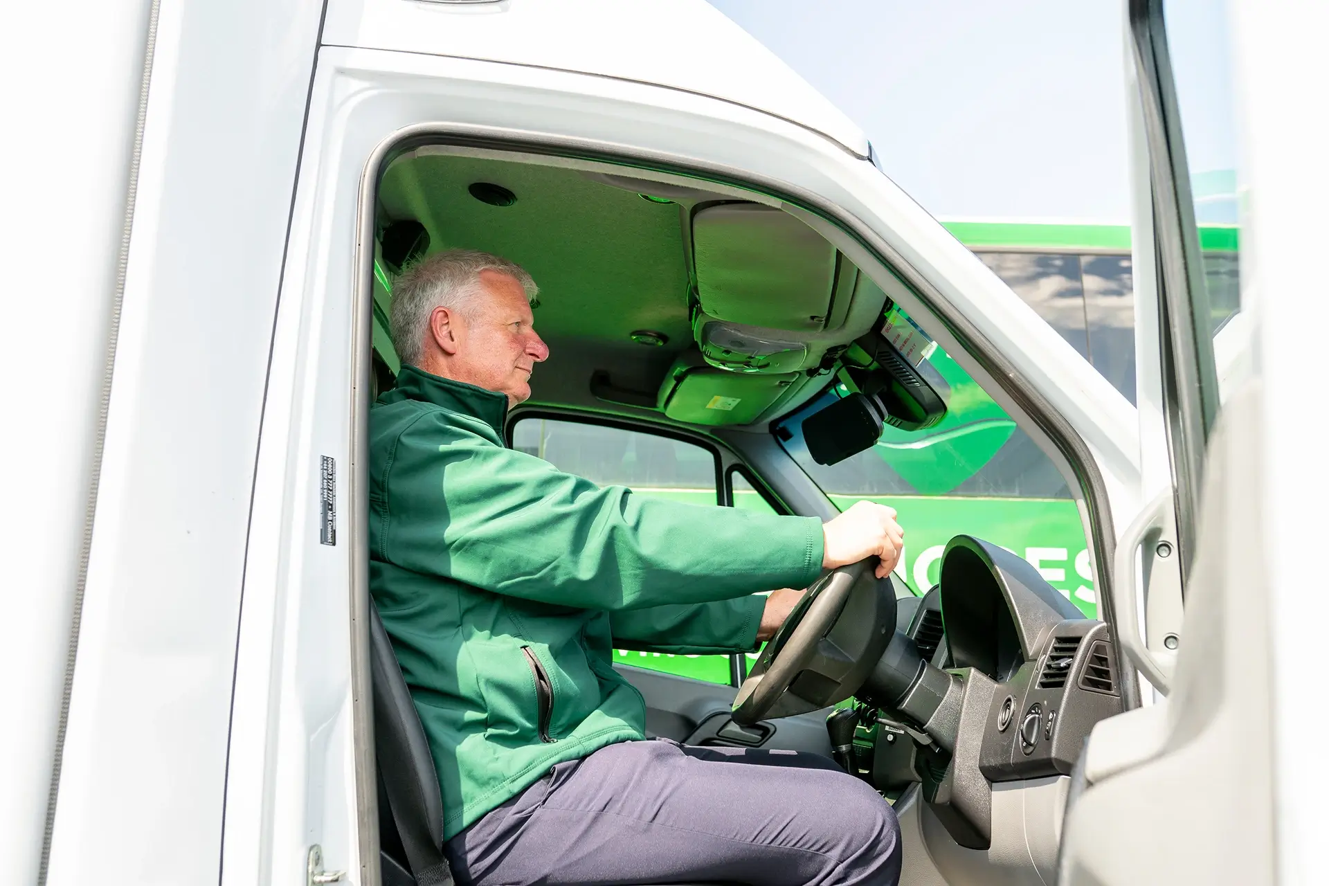 A_man_wearing_a_green_jacket_is_driving_a_truck_on_a_road_ISM_Driving_lessons